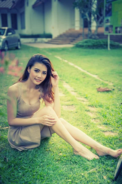 Ásia bela menina sentado no parque na grama verde — Fotografia de Stock
