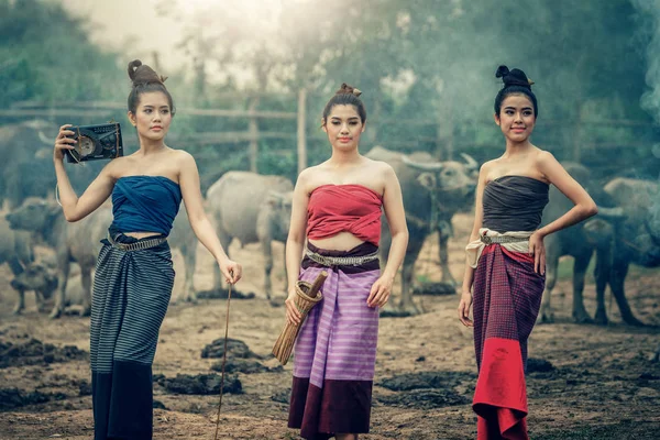 Three Asian women dressed in national costume with buffalo at fa — Stock Photo, Image