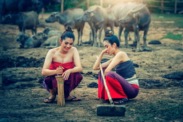 Dos mujeres asiáticas vestidas con traje nacional con búfalo en la granja — Foto de Stock