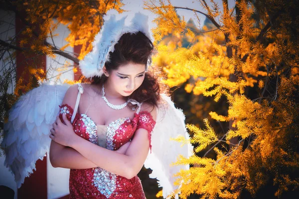 Hermosa mujer con alas de ángulo de vestido rojo posando en el jardín — Foto de Stock