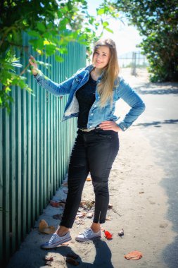 Yeşil çitlere karşı tek başına duran güzel genç bir kadının portresi..