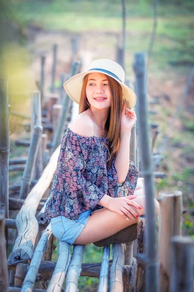 asia woman in Off  Shoulder shirt and short jeans with hat sitting on nature