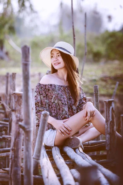 asia woman in Off  Shoulder shirt and short jeans with hat sitting on nature