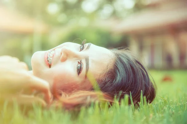 Девочка лежит на зеленой траве, отдыхая в парке . — стоковое фото