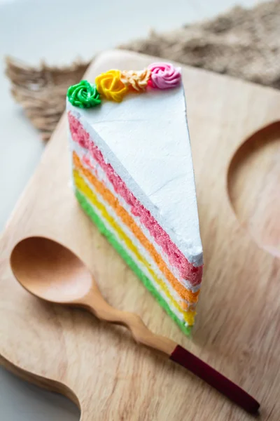 Delicioso bolo de arco-íris em placa de madeira . — Fotografia de Stock