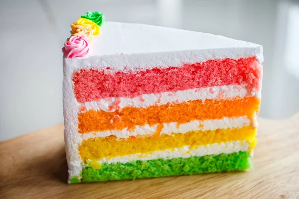 Delicious rainbow cake on wood plate. — Stock Photo, Image