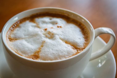 Ahşap masa üzerinde sıcak cappuccino Kupası.