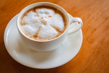 Ahşap masa üzerinde sıcak cappuccino Kupası.