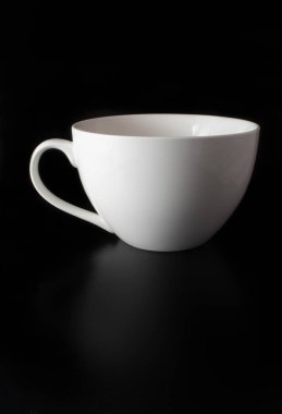 Siyah arkaplanda beyaz porselen bardak