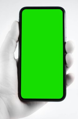 Beyaz arka planda boş yeşil ekranlı cep telefonu erkeğin elinde.