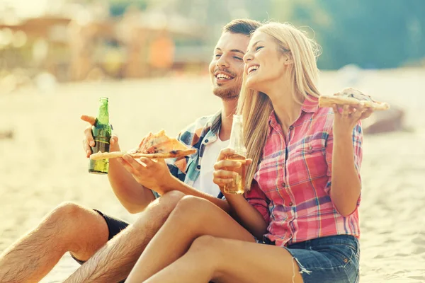 Amor casal comer pizza e beber cerveja na praia — Fotografia de Stock