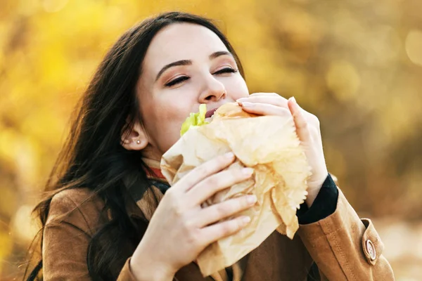 Głodny młoda kobieta korzystających Sandwich na zewnątrz — Zdjęcie stockowe