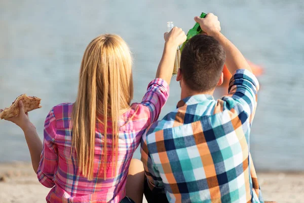 Amor pareja comiendo pizza y beber cerveza en la playa —  Fotos de Stock