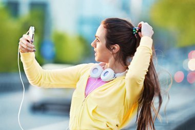 Güzel genç kadın rahatlatıcı koşu sonra cep telefonu ile
