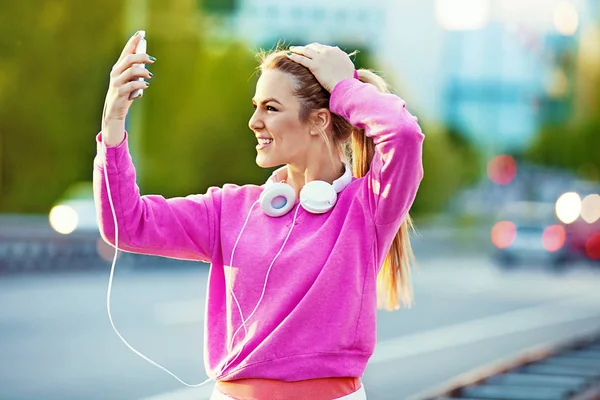 Hermosa mujer joven que se relaja con el teléfono celular después de correr — Foto de Stock