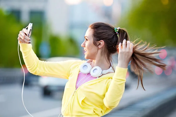 Hermosa mujer joven que se relaja con el teléfono celular después de correr — Foto de Stock