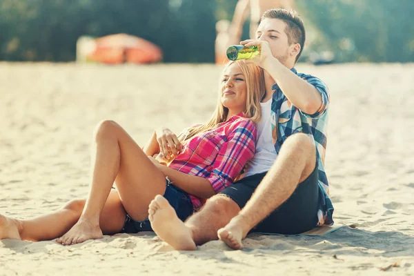 Pareja joven bebiendo cerveza en la playa — Foto de Stock