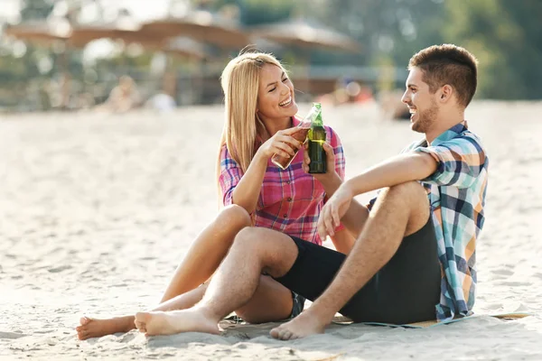 Jong (echt) paar Driniking biertje op het strand — Stockfoto