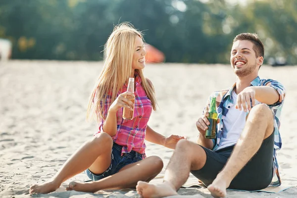 Pareja joven bebiendo cerveza en la playa — Foto de Stock