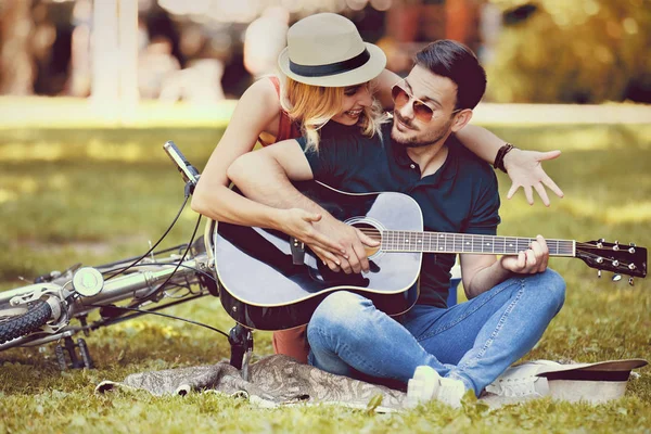 Любов пара насолоджуючись гітарою в парку — стокове фото