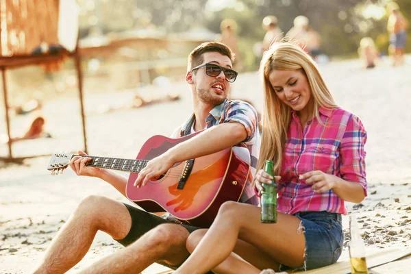 Młody człowiek gra gitara do jego dziewczyna — Zdjęcie stockowe