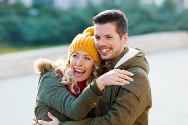 Gülümseyen çift birbirlerine bir sonbahar günü sarılma.  