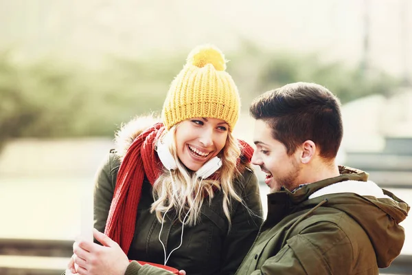 Casal sorridente usando celular em um dia de outono . — Fotografia de Stock