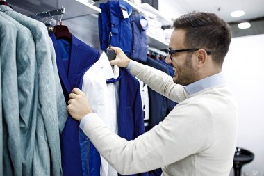 Gülümseyen genç adam bir gömlek satın