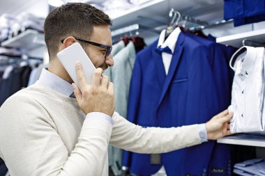 Gülümseyen genç adam bir gömlek satın