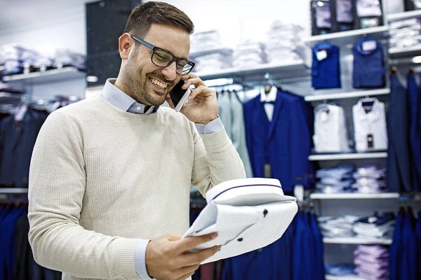 Sorridente giovane uomo comprando una camicia — Foto Stock