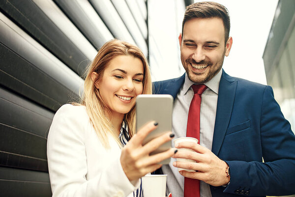 Young business people are relaxing in front of the company building and discussing about new project.