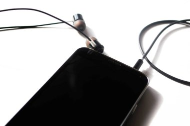 Beyaz arka planda kulaklıklı telefon.