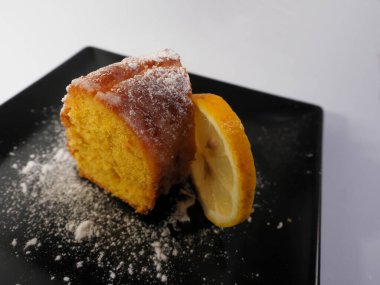 Siyah tabakta kremalı limonlu kek.