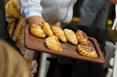 Parmak gıda garson tarafından yaptı. Detay Empanadas, Arjantinli geleneksel yemekleri. Detay ahşap plaka, yiyecek ve el.