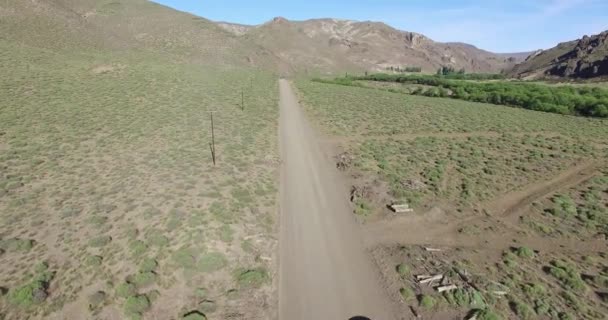 Escena aérea de drones de carretera de grava en estepa y furgoneta avanzando. Montañas en el fondo. Movimiento estático de la cámara. Paisaje rural del desierto en Patagonia Argentina . — Vídeo de stock