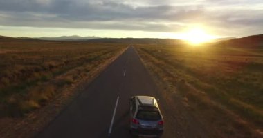 Hava uçak olay yerinde Bozkır ve van rotanın günbatımı altın saat hareketli ileri de adam bisiklet içinde görünür. Arka planda dağlar. Yolu üzerinden uçan kamera. Çöl kırsal manzara, Patagonya.