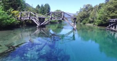 Hava dron sahne. Cristal net, turquioise, şeffaf nehir, ruca malen trivutary correntoso Gölü'nün üzerinde eski ahşap kırık köprü. Kamera yükselir olabilir nehir ağzı gördün. Patagonya Arjantin.
