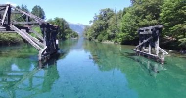 Hava dron sahne. Cristal net, turquioise, şeffaf nehir, ruca malen trivutary correntoso Gölü'nün üzerinde eski ahşap kırık köprü. Kamera yükselir olabilir nehir ağzı gördün. Patagonya Arjantin.