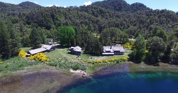 Escena aérea de drones de ruta y nuevo puente con plantas amarillas en el sur de Patagonia, lago Correntoso y hotel abandonado. Barco de pesca rojo en la costa. Cámara avanzando. Puente viejo roto de madera . — Vídeo de stock