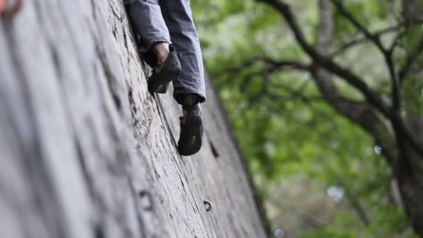 Rock climbing detail of climber shoes on straight vertical wall. Man with locked carabiner and grigri catching the rope with rustic hands about to belay. Slow motion 120fps detail close up. Risk sport — Stock Video