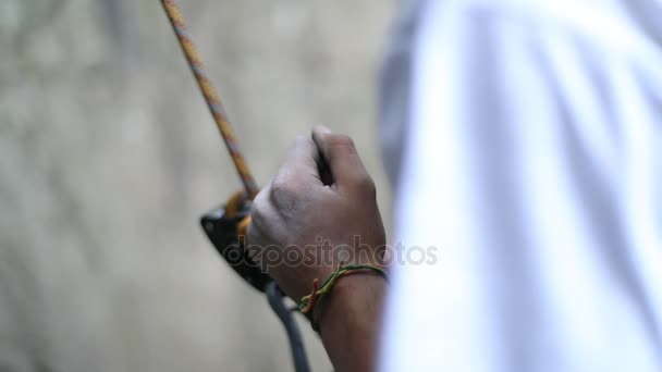 Cintura de escalador adulto con un grigri y un mosquetón unidos al arnés. Detalle de sus manos y la cuerda que pasa por los grigri. A cámara lenta, 120 fps. Patagonia, Argentina. Deporte de riesgo extremo . — Vídeos de Stock