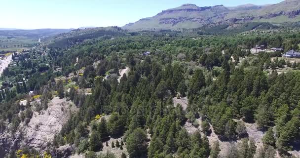 Letecké drone scéně z domů v lese v horách jižní Patagonie, Argentina, město San Martin de los Andes s Chapelco mountain v pozadí. Větrný den a stromy hýbají. — Stock video