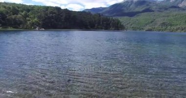 Göl Patagonya Arjantin Hava dron sahne. İleri hareketli kamera, gölün diğer tarafında için yeşil çim kıyıdan üzerinden hızlı ve suya yakın. San Martin de los Andes.