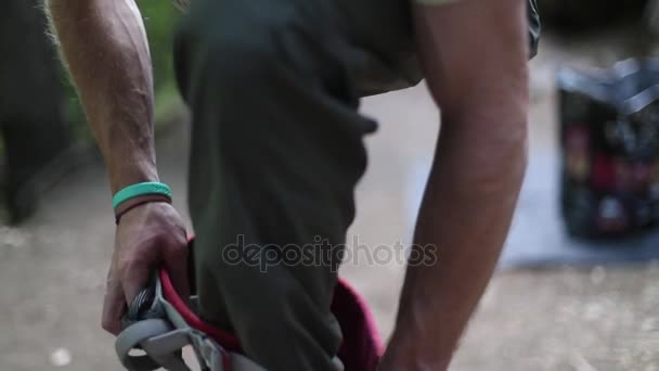 Detail in Zeitlupe bei 120 fps eines starken erwachsenen Bergsteigers, der sein Gurtzeug durch seine Beine zieht und sich bereit macht, zu klettern oder sich zu verstecken. Extremrisikosport. Patagonien, Argentinien. — Stockvideo