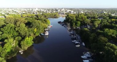 Nehir deltası üzerinde uçan hava aracı sahnesi her iki kıyıda da demirli, arka planda Gualeguaychu şehrinin panoramik manzarasına yükseliyor. Entre rios, Arjantin.