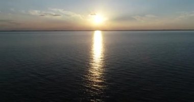 Güneş batarken suyun üzerinde uçan hava aracı sahnesi, altın saat. Yansıma, renkli bulutlar. Las Caas, Rio Negro, Uruguay