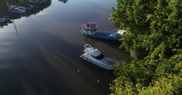 Drohnen-Szene aus der Luft, die das beschauliche Flussdelta mit Fischerboot und Jacht zeigt, die bei Sonnenuntergang am Ufer festmachen, goldene Stunde, Lichtband. zur Ansicht von oben, die Details der Yacht zeigt. gualeguaychu, entre rios, argentinien — Stockvideo