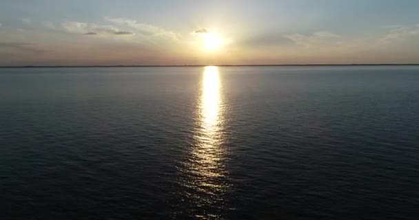 Scène de drone aérien volant au-dessus de l'eau vers le soleil au coucher du soleil, heure d'or. Réflexion, nuages colorés. Las Caas, Rio Negro, Uruguay 