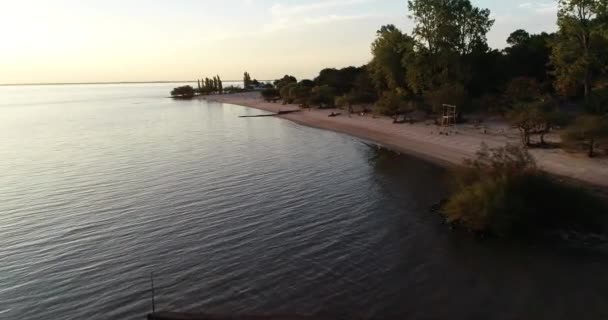 Εναέρια drone σκηνή της παραλίας στο φυσικό τοπίο στο ηλιοβασίλεμα. Πετώντας κατά μήκος της παραλίας της άμμου και του δάσους στον ποταμό Ουρουγουάη. Το φόντο του ποταμού. Las Caas, επαρχία Rio negro, Ουρουγουάη — Αρχείο Βίντεο