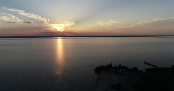 Drohnen-Szene aus der Luft, die über Strand und Vegetation fliegen, bei Sonnenuntergang, goldene Stunde. Orange, gelbe Sonne am Horizont. uruguay fluss, caas, rio negro. — Stockvideo